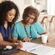 Female healthcare worker filling in a form with a senior woman during a home health visit